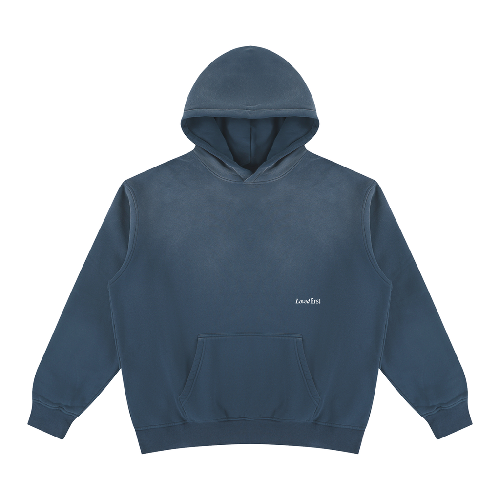 A Washed Blue blue pullover hoodie with a small white printed 'LovedFirst' logo on the left chest, displayed on a clean white background.