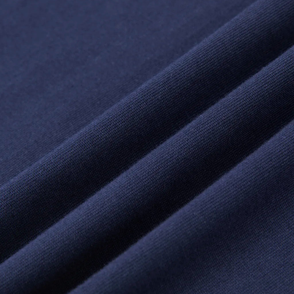A close-up of dark navy blue fabric with soft diagonal folds showing the texture and color of the material.